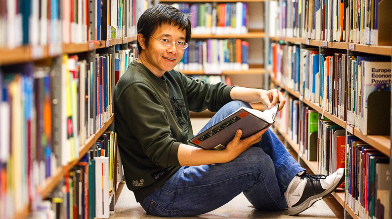 phd in economics student reading in the library